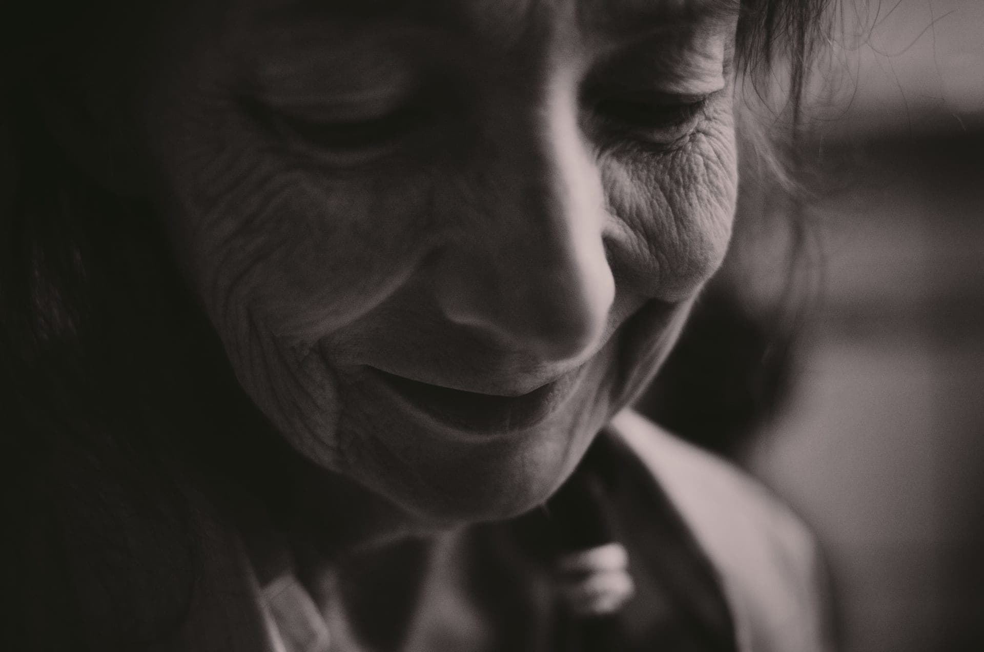 A black and white close-up of a smiling senior woman's face with her eyes closed