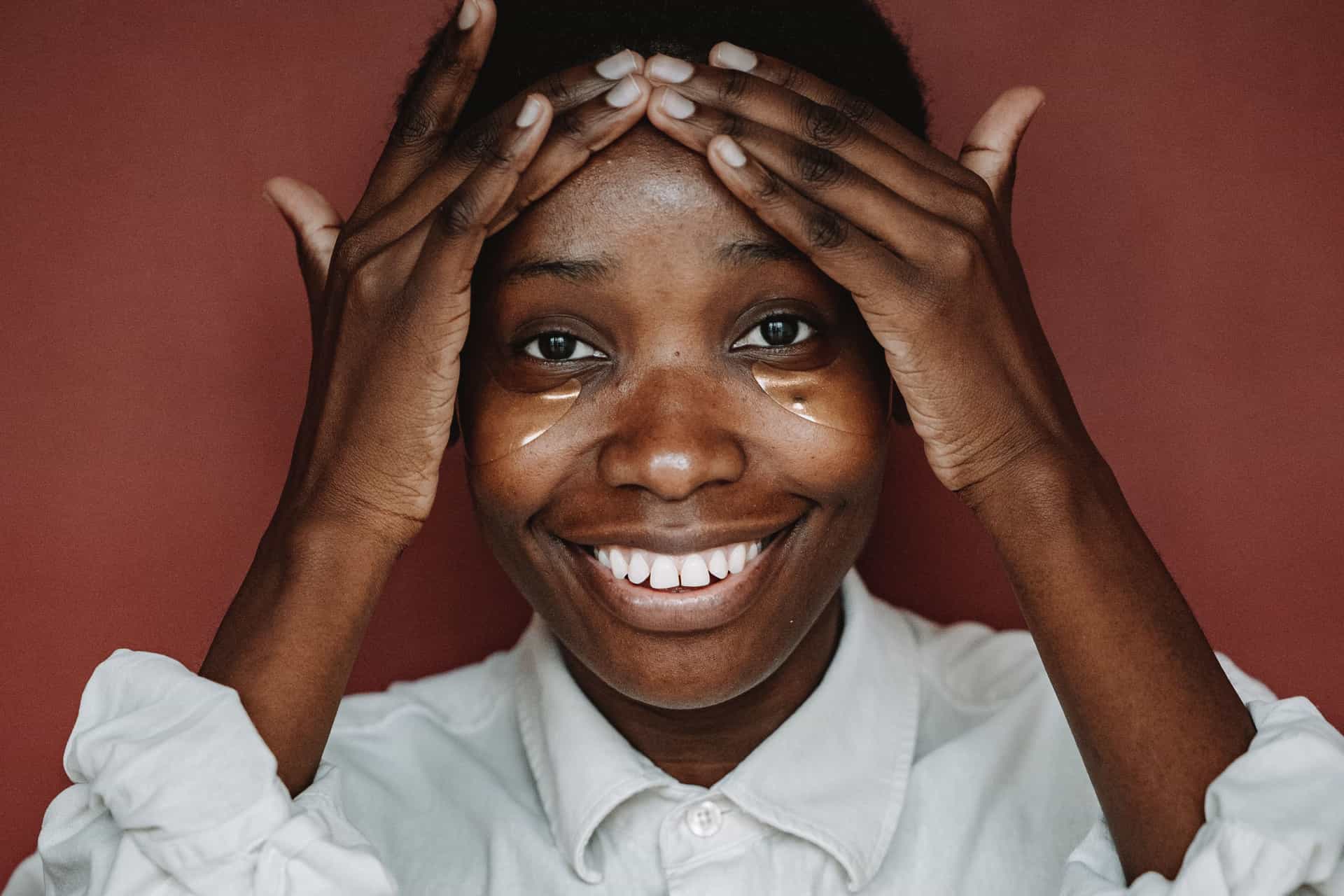 A woman applying under-eye patches as part of a morning skincare routine